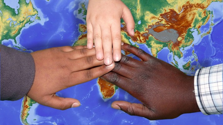 Tre händer med olika hudfärg på en jordglob.