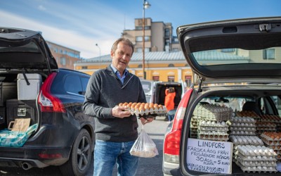 Thomas Snellman står med en äggbricka vid en bil på torget i Jakobstad.