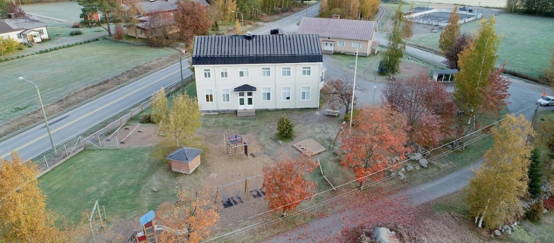 Flygbild över Sundby skola och lärarbostäderna i bakgrunden.