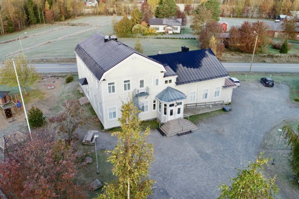 Sundby skolfastighet, fotograferad från luften. Delar av skolgården, landsvägen och hus på andra sidan vägen syns.
