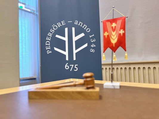 En ordförandeklubba och Pedersöres bordsstandard på ett bord.