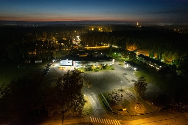 En översiktsbild av Sandsund skolområde på kvällen när belysningen är på. Det är annars mörkt.