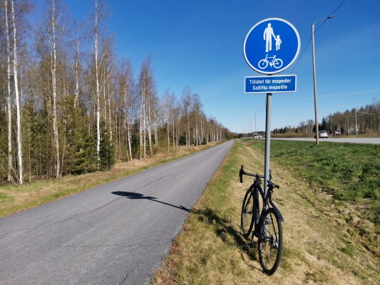 Pyörätie Remson varrella Lövössä. Polkupyörä nojaa pyörätien liikennemerkkiin.