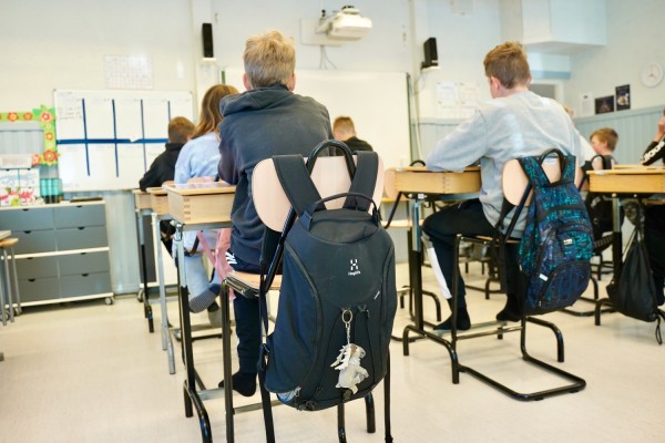 Elever sitter vid sina bord i ett klassrum.
