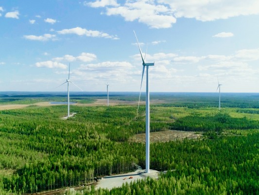 Fyra vindkraftverk i en skogsmiljö.