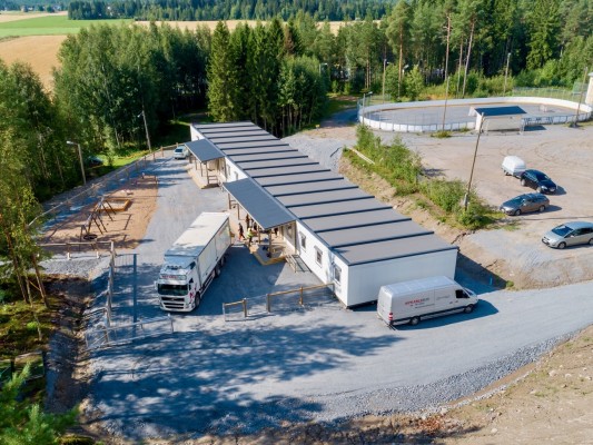 Modulen som är placerad vid skogsbrymet. På bilden finns också en lastbil som för möbler till förskolan. En del av skolgården syns, med bland annat hockeyrinken.