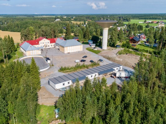 Dronekuva Kolpin koulualueesta. Koulu, vesitorni ja esikoulun uusi moduuli metsän vieressä.