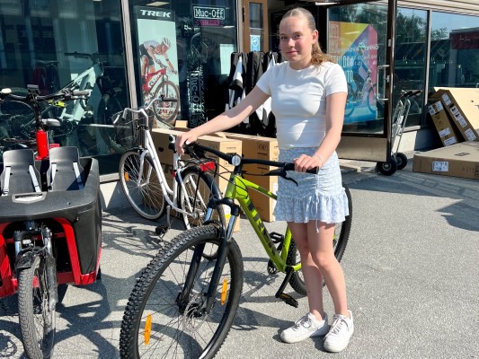 Ines Anderssén seisoo pyöräliikkeen ulkopuolella uusi Trek-pyörän kanssa.