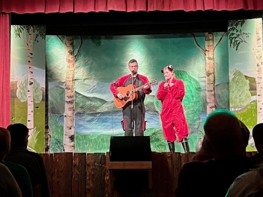 Två personer står på scenen och sjunger och spelar gitarr. Det är Esserevyn.