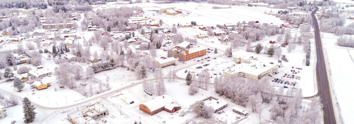 Flygbild över Bennäs bycentrum. Kommungården, kulturhuset, den gamla verkstaden, Purmovägen och industriområdet syns.