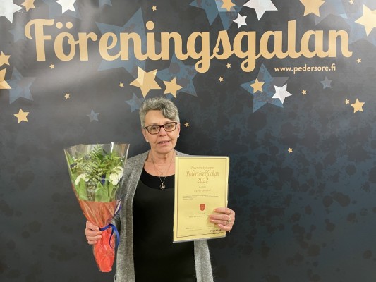 Carina Rönnlund, som fick Pedersöreklockan, står med blommor och diplom i hand framför en vägg med Föreningsgalans logo.