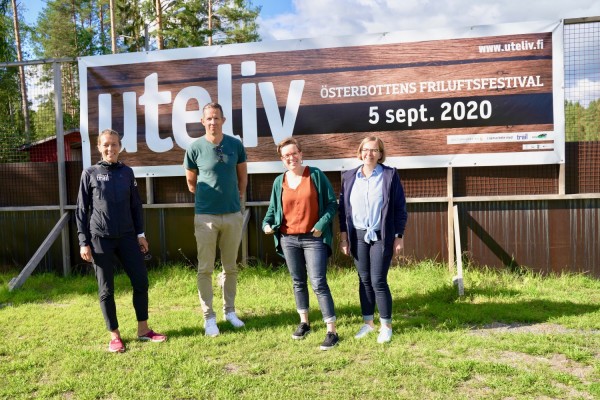 Fyra personer ur arrangörsstaben står framför evenemangsaffischen för festivalen Uteliv i Lappfors 5 september.