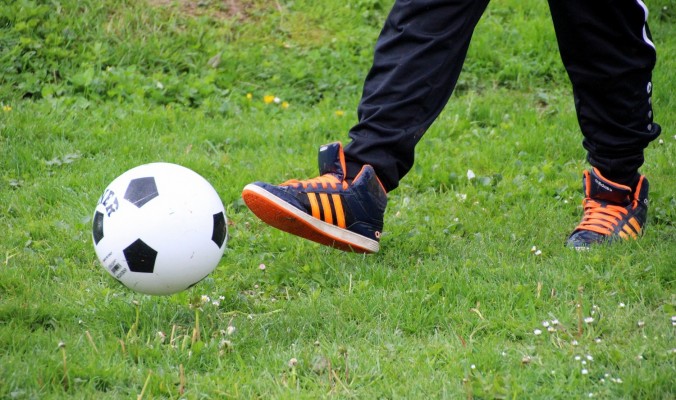 Fotboll och fot på gräsmatta.