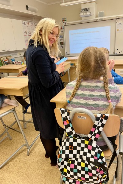 Hanna Lundström keskustelee istuvan oppilaan kanssa luokkahuoneessa.