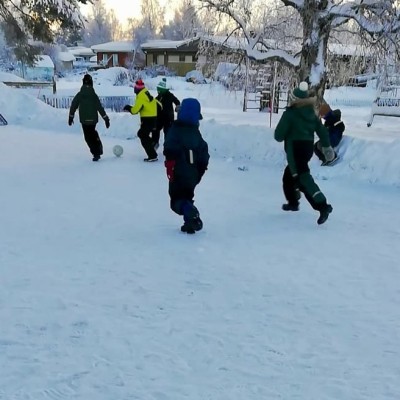 Barn spelar fotboll i snön.