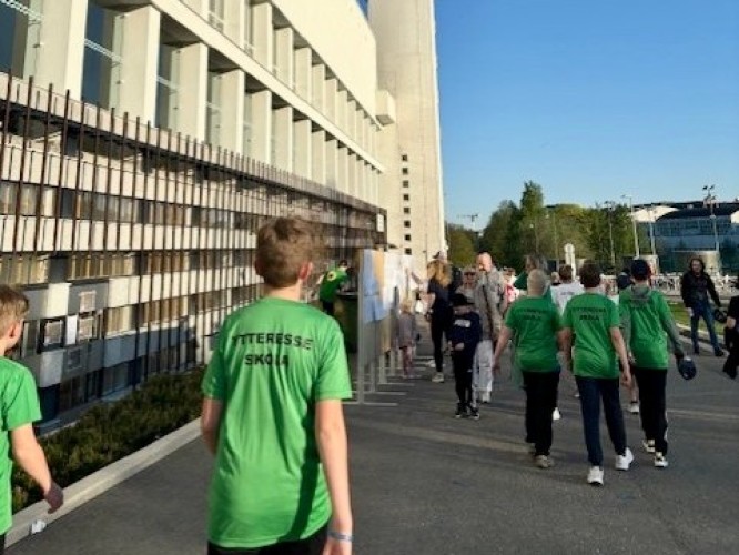 Några barn går utanför Olympiastadion. De har på sig gröna tröjor med texten "Ytteresse skola" på ryggen.