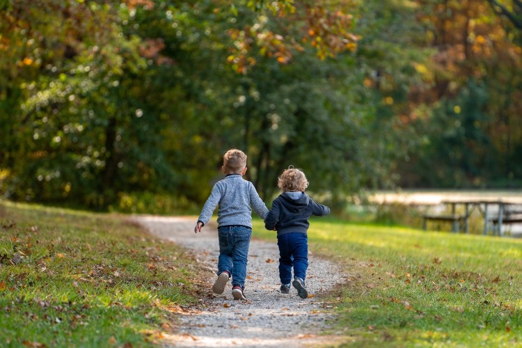 Två små pojkar springer hand. hand på en grusväg.