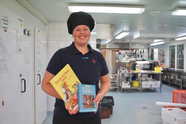 Ida Lillqvist pitää lastenkirjoja kun hän seisoo Sursik skolanin keittiössä.