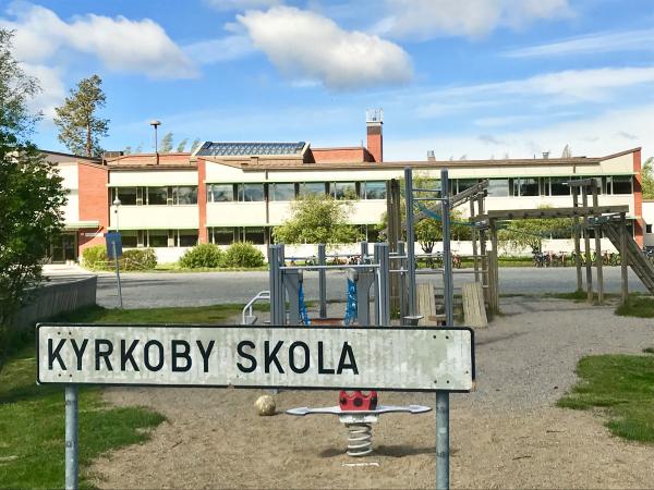 Skylt med Kyrkoby skolas namn på skolgården.